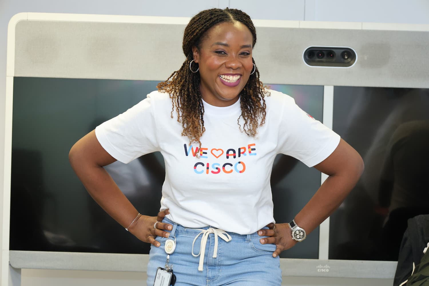An employee poses in front of a Webex board proudly wearing her We Are Cisco shirt.